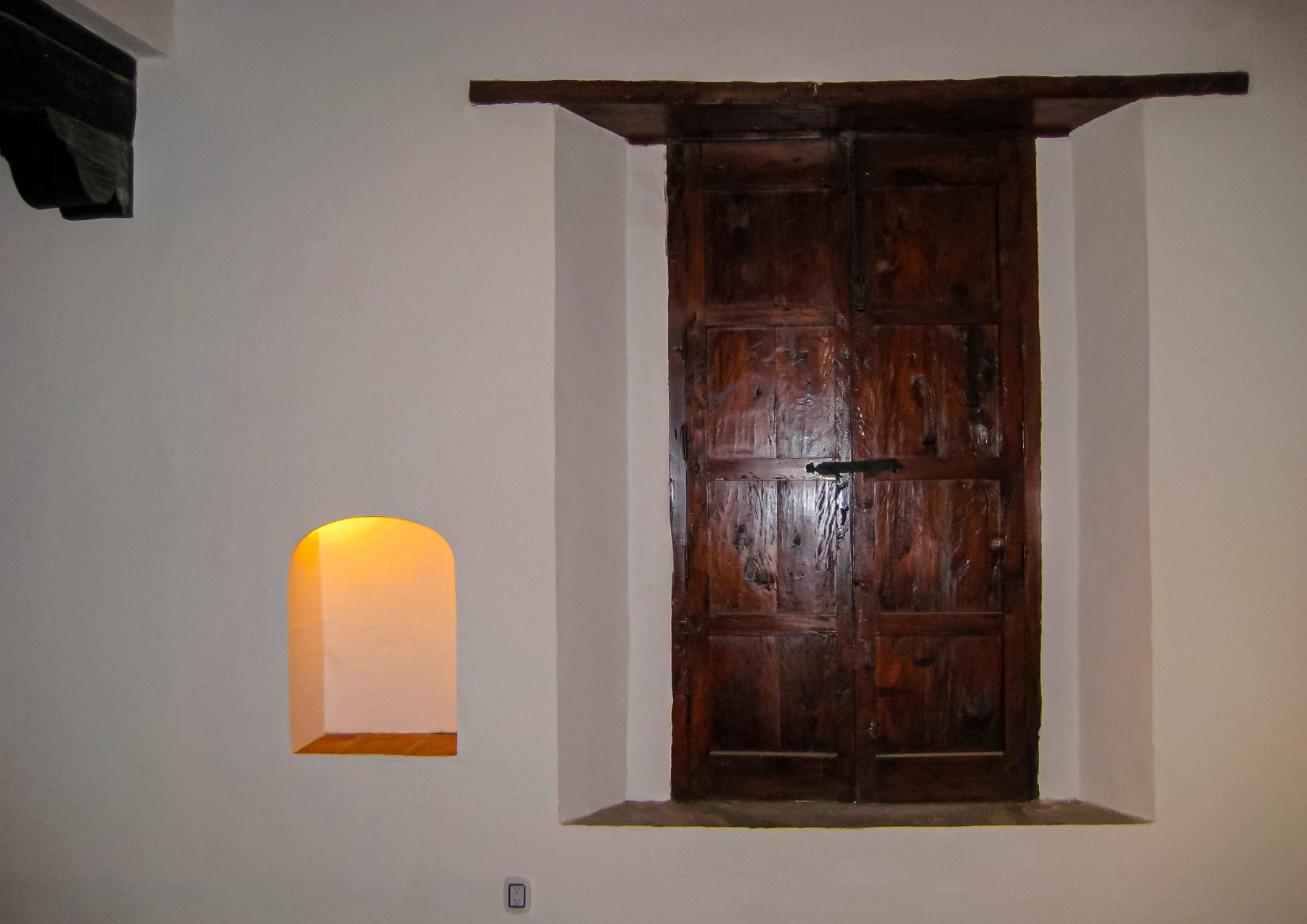 Puerta de madera restaurada y nicho en muro encalado, Taxco